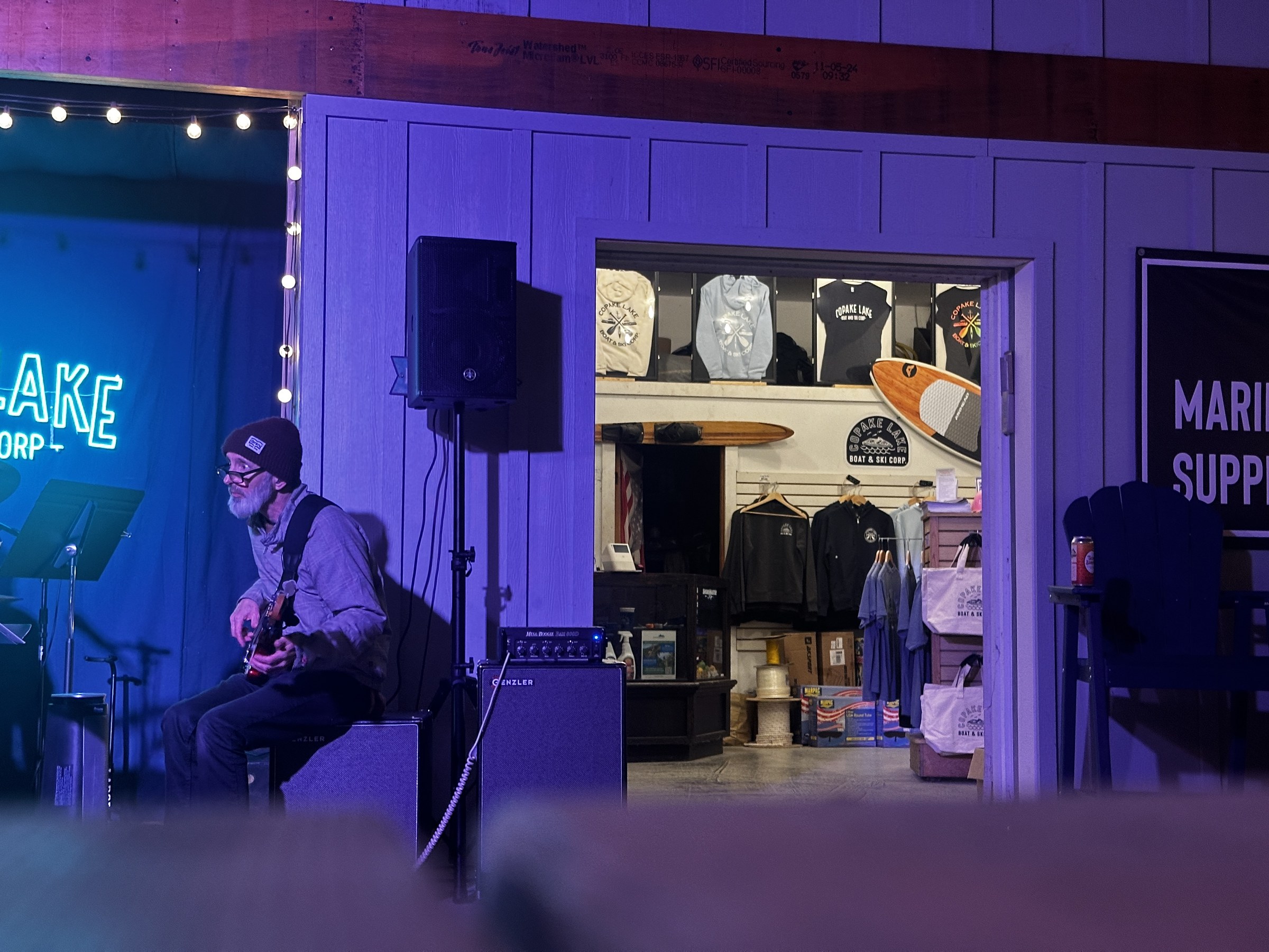 A musician playing beside the Copake Lake Boat and Ski shop