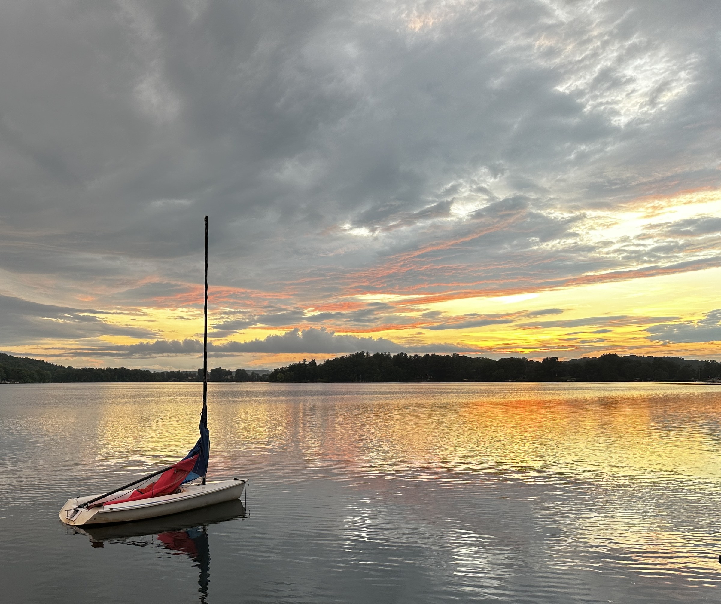 A small sailboat at rest on an upstate lake beneath an evening sky
