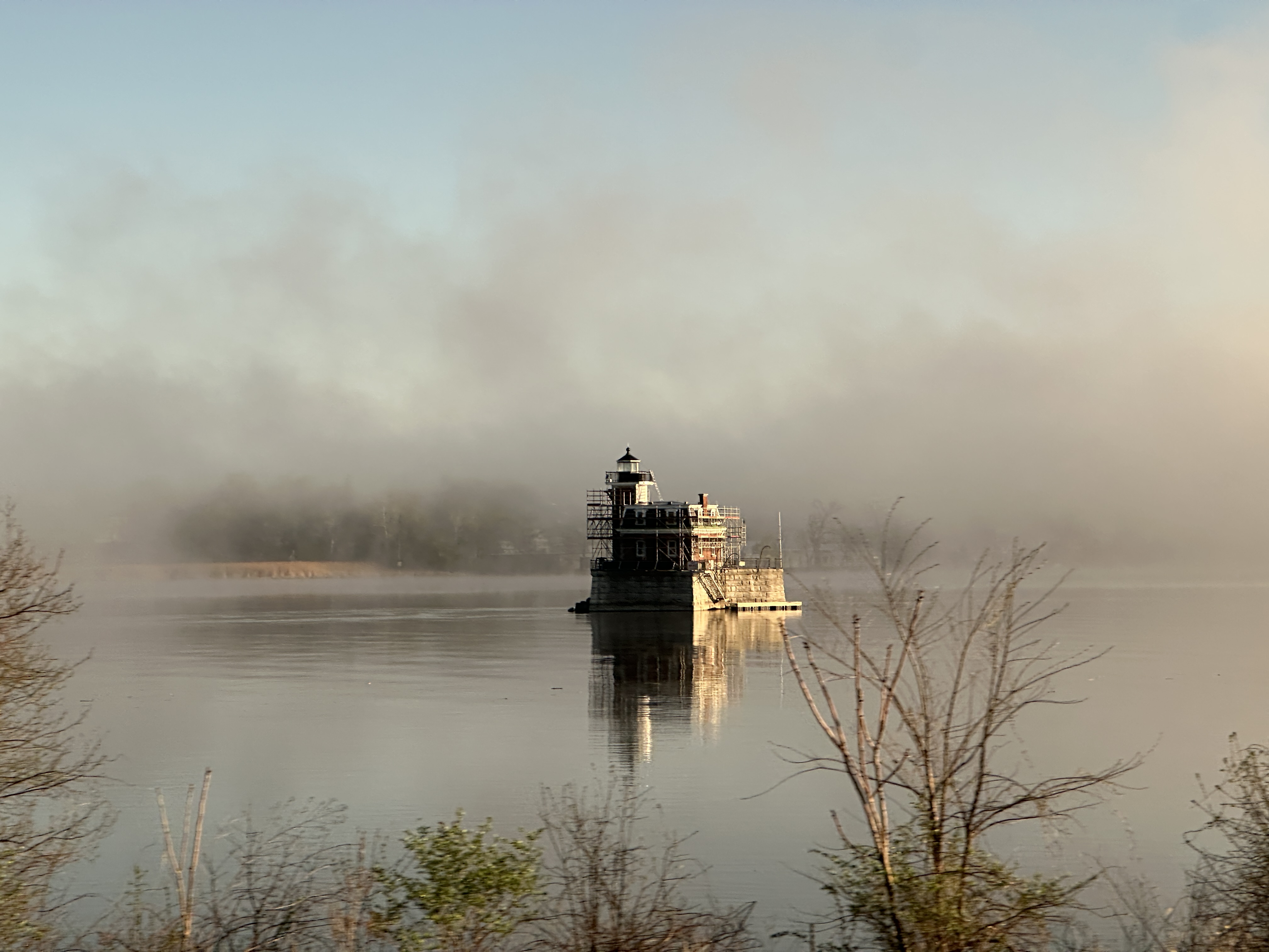 A historic lighthouse-like structure reflected in misty water